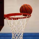 A basketball moment captured as the ball rests on the rim, highlighting the suspense of the game.
